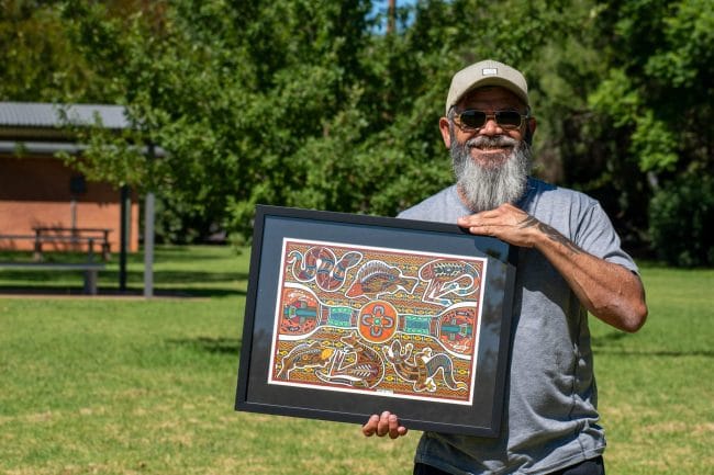 Wiradjuri Artist holding his finished artwork in a park
